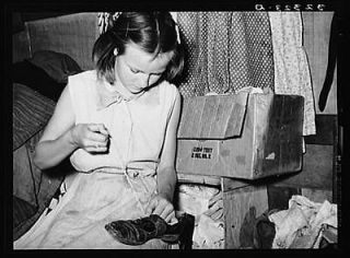 Daughter of white migrants repairing shoes with cotton thread 